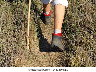 Pilgrim With Boots Walking Along The Path Near Castilblanco In Via De La Plata At Province Of Seville  Andalusia. Via De La Plata Is St. James Way (Camino De Santiago) From Seville To Santiago