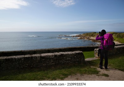A pilgrim who makes the Portuguese Camino de Santiago along the coast makes a stop to photograph the sea in front of the Oia monastery