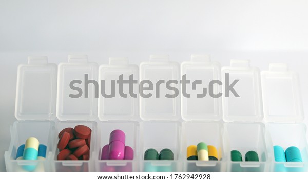 Pill box daily take a medicine, with colorful of\
pills, tablets, and capsules. Drugs use for treatment and cure the\
disease. Medication in medical clinic isolated in white background,\
has copy space.
