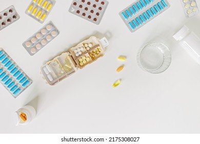 Pill Box Daily Taking Medicine, With Tablets And Capsules. Drugs, Medication As Alternative Medicine For Treatment And Good Health. Medicine Dose Box With Pills And Glass Of Water On Table, Flat Lay