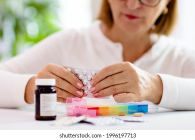 Pill box for senior patient. Medicine container. Elderly woman sorting drug pills for pain relief and disease treatment. Sick retired female with drugs. Daily vitamins for healthy retirement. - Powered by Shutterstock