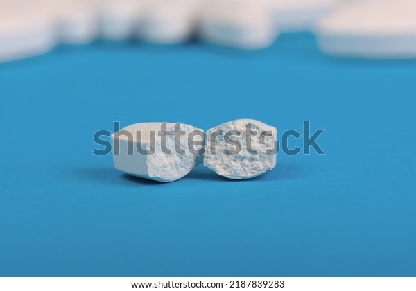 Pill broken into two parts on a blue\
background with space for text. Selective\
focus.