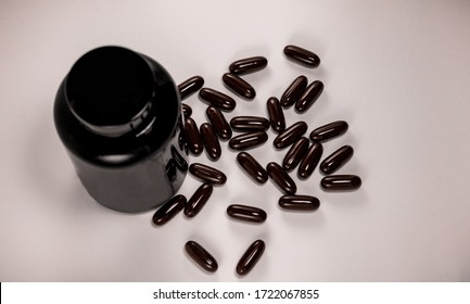 Pill capsules in brown tone isolated and medicine black bottle for container in white background