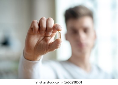 Pill. Close up picture of a young man holding a pill