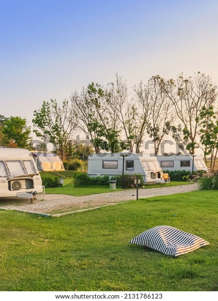 Pillow or mattress for relax on green grass\
with Cozy retro travel trailer Caravan near riverside in peaceful\
countryside.Family vacation travel RV, holiday trip in\
motorhome.Outdoor and\
Recreational
