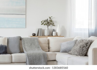 Pillows and blanket on comfortable beige corner sofa in classy living room