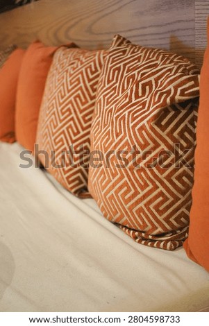 Pillows with a geometric pattern sit on a white sofa in a room.