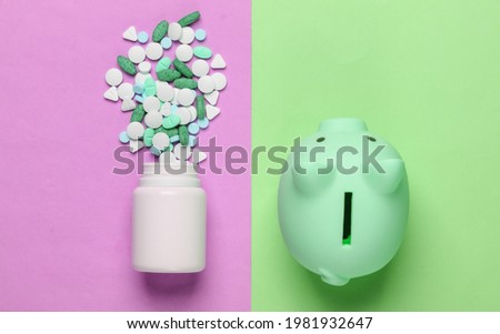 Pills bottle with piggy bank on pink green pastel background. Top view