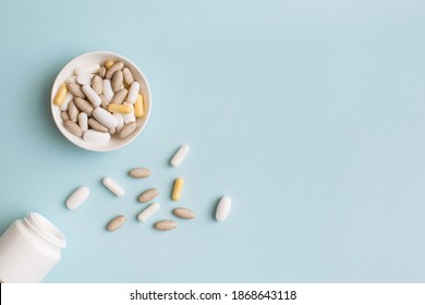 Pills, capsules, vitamins and natural organic food supplements on white plate on light blue background. Minimal modern pharmacy or health care concept. Flat lay, top view, copy space