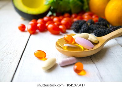 Pillen und Kapseln in Holzlöffel mit frischen Früchten.Multivitamins und Ergänzung aus dem Obstkonzept.