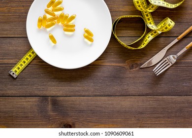 Pills Or Dietary Supplement For Weight Loss. Treatment Of Obesity. Treatment Of Anorexia. Gold Pills On Plate Near Measuring Tape On Dark Wooden Background Top View Copy Space