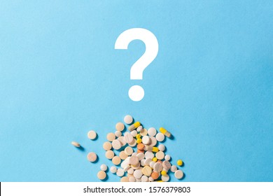 A lot of pills of different types and a question mark on a blue background. Insomnia, taking pills according to the regimen, vitamins. Flat lay, top view