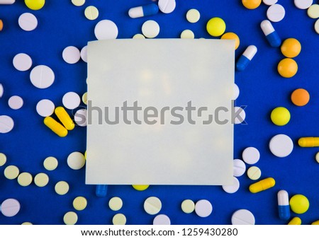Pills and Empty Paper on the Blue Cardboard Background