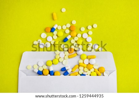 Pills with an Envelope on the Yellow Paper Background closeup