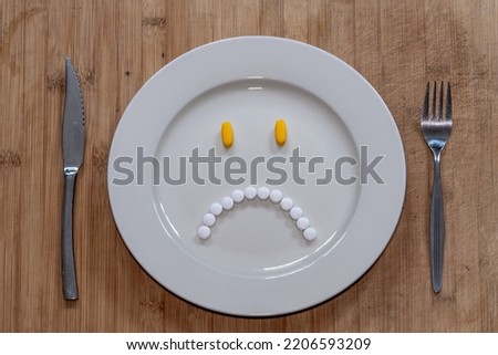 Pills on the plate in the shape of miserable and unhappy face, healthcare, dieting or taking medication concept