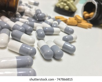 Pills And Opioid Addictions Open Pill Bottle On White Counter Big Pharma Makes Lots Of Money Off Of The Pharmaceutical Industry Close Up On Capsule