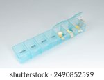 Pills organizer with supplements on yellow background  top view. Capsules in daily organizer. Weekly pillbox. Clear plastic pill container and medications. High quality photo