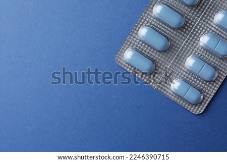 Pills and space for text on blue background, top view. Potency problem