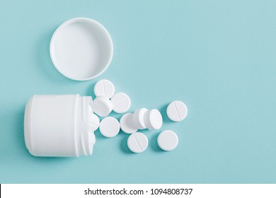 Pills Spilling Out Of Pill Bottle On Blue Background, Top View