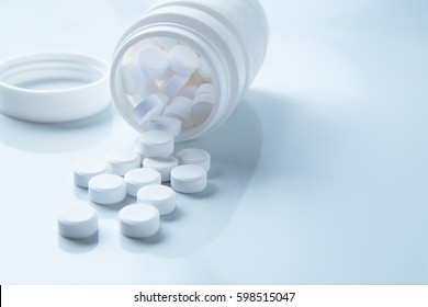 Pills spilling out of pill bottle on white. with copy space. Medicine concept