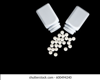 Pills Spilling Out Of Pill Bottle And Isolated With Clipping Path On Black. Top View With Copy Space. Medicine Concept