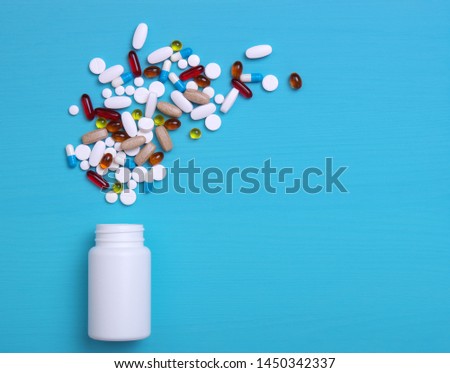 Pills, tablets and capsules on wooden blue background