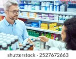 Pills, talking and pharmacist with customer in dispensary with box of prescription medication. Healthcare, medicine and mature male medical dispenser consulting shopper with tablets for side effects.