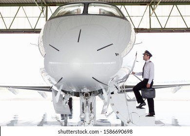 Pilote embarquant dans un jet privé dans un hangar : photo de stock