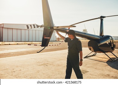 Pilot checking tail wings helicopter during preflight checklist on a sunny day. Engineer doing pre flight inspection.