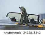 A pilot and co pilot in a G-suit inspects a fighter jet. Control panel area on the side of the aircraft fuselage. Check readiness before flying.