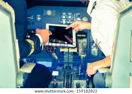Pilot and Copilot Checking Flight Information on Digital Tablet