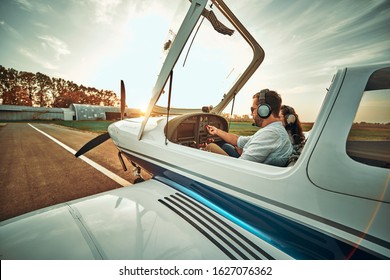 Pilot With Co-pilot Prepare Take Off In A Small Aircraft. Side View. Sunset Background