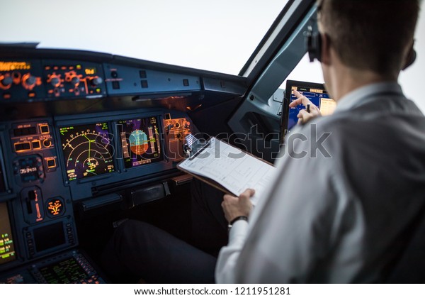 Pilot executing pre-flight procedures in a\
commercial airliner cockpit before\
takeoff