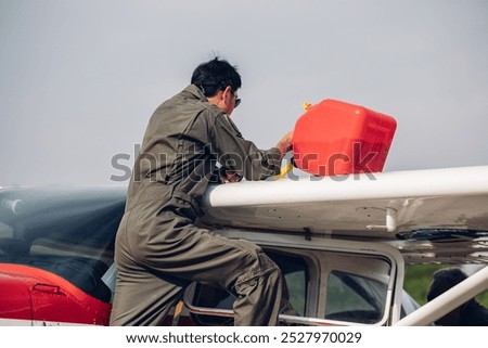 Pilot fueling low-wing propeller driven airplane. Refueling fuel in an aircraft wing. Aviation fuel being  into wing tank of a small airplane
