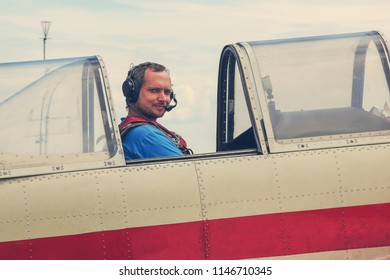 Pilot in headphones and a speakerphone in the cockpit before takeoff. Man and plane before the flight.
