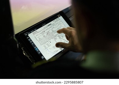 the pilot holds a tablet in his hands, looks at the flight route and chooses the landing place of plane
