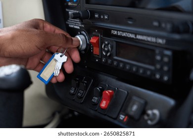 Pilot inserting key in ignition switch of aircraft cockpit panel