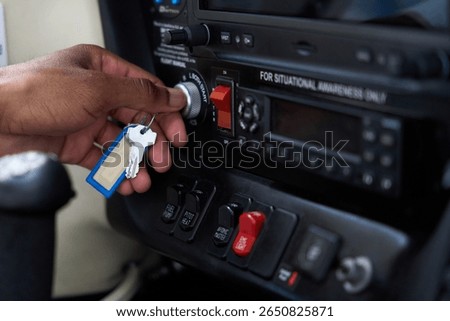 Pilot inserting key in ignition switch of aircraft cockpit panel