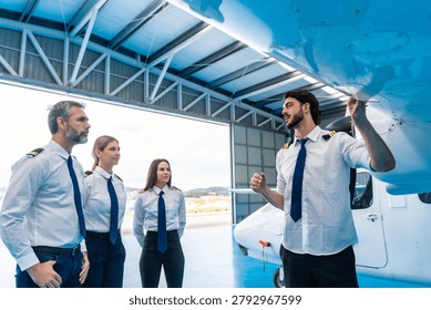 Pilot instructor explaining pre flight inspection procedures of a small aircraft wing to a group of aspiring pilots in a professional aviation school environment