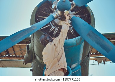 Pilot Or Mechanic In A Full Flight Gear Checks The Propeller Of His Retro Military Aircraft Before A Flight.