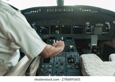 Pilot operating controls in a private jet cockpit with illuminated instruments and flight deck view