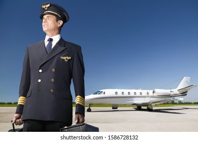 Pilot Of Private Jet Standing By Aircraft On Tarmac