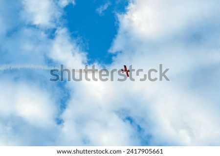 Similar – Red plane with propeller flying upward with white smoke