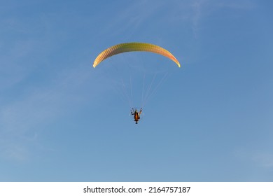 The pilot took off into the sky on an individual backpack parajet with a gasoline engine. Flying with a motorized wing. Extreme sports. Paraglider and small aircraft.