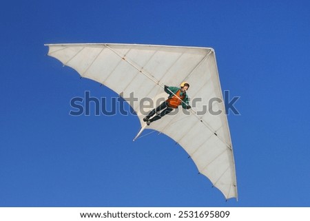 Pilot-driven hang glider flies high in the blue sky