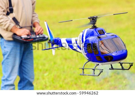 Piloting Radio controlled helicopter (scale-model 1:24 scale) with remote control. Teleobjective shot with shallow DOF.
