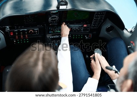 Pilots operating sophisticated control panel and instruments in a modern light aircraft cockpit, gaining flying experience