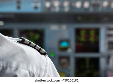 Pilot's shoulder with a badge in an aircraft cockpit.