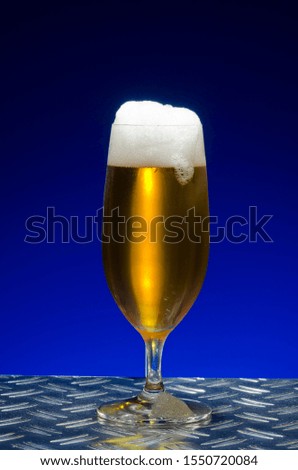 Pilsener beer, beer with a head in a traditional pils glass, on metal table