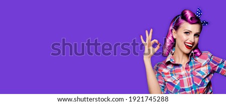 Pin up girl. Portrait photo of excited happy smiling purple hair woman showing ok hand sign gesture. Retro and vintage concept. Violet color background. Caucasian model posing at studio. Copy space.